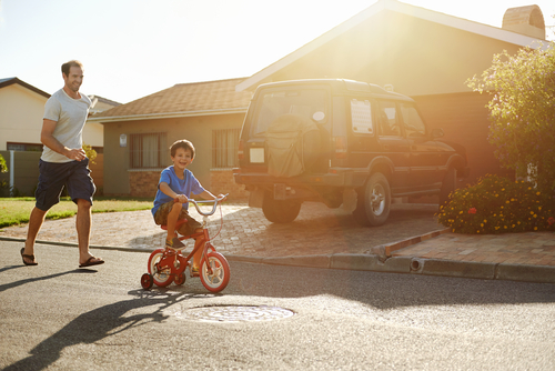 Father teaching son to ride bike – Good neighbors equal positive real estate investment