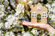 hand holdig small model house, cherry blossoms, spring real estate