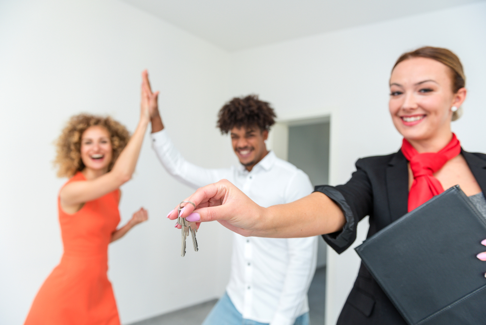 Happy landlord holding keys, happy tenants doing high five