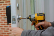 Man repairing lock on door – Rental property safety maintenance tips