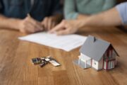 people signing loan documents, keys, model of house