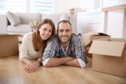 Smiling couple on floor, moving boxes, nice room