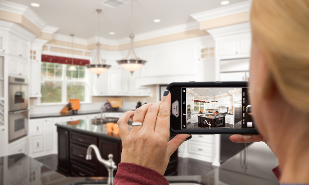 woman taking photo of kitchen, real estate listing